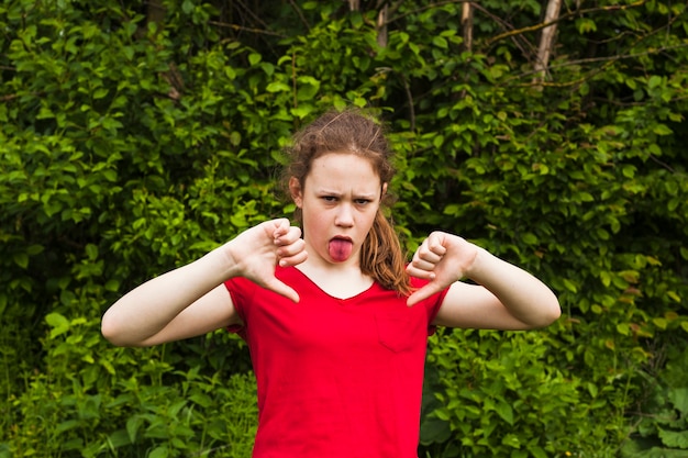 Ragazza che prende in giro con attaccare fuori lingua che esamina macchina fotografica in parco