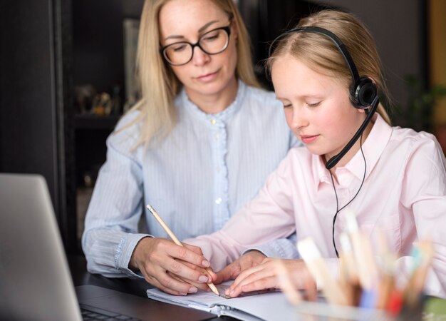 Ragazza che prende le note accanto all'insegnante a casa