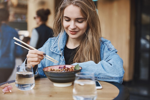 Ragazza che prova cibo asiatico per la prima volta appoggiata sul tavolo mentre st