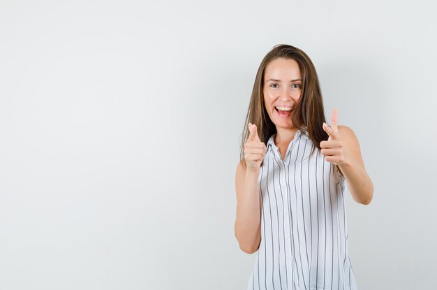 Ragazza che punta alla telecamera in t-shirt e alla ricerca energica, vista frontale.