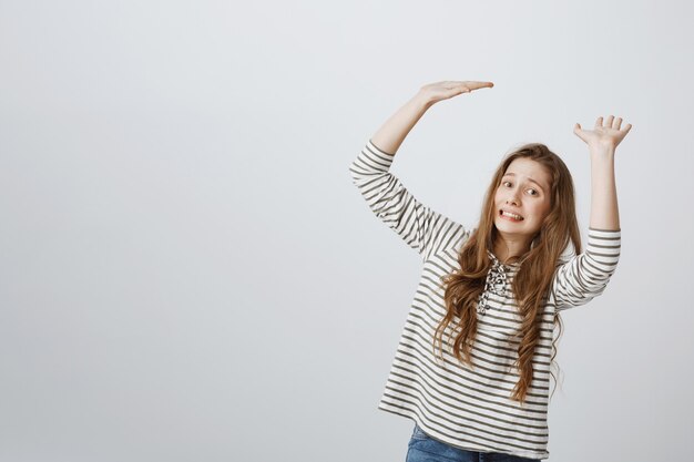 Ragazza che sembra a disagio mentre tiene qualcosa di grande