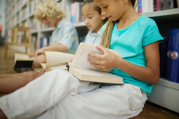 Ragazza che sfoglia il libro seduto con gli amici sul pavimento