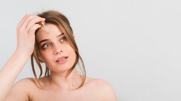 Ragazza che si applica prodotto cosmetico