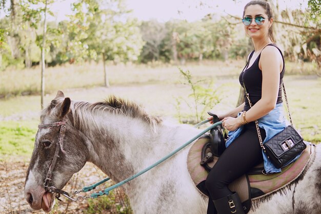 Ragazza che si prepara a cavalcare un cavallo