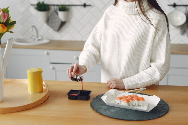 Ragazza che si siede a casa al tavolo con un sushi