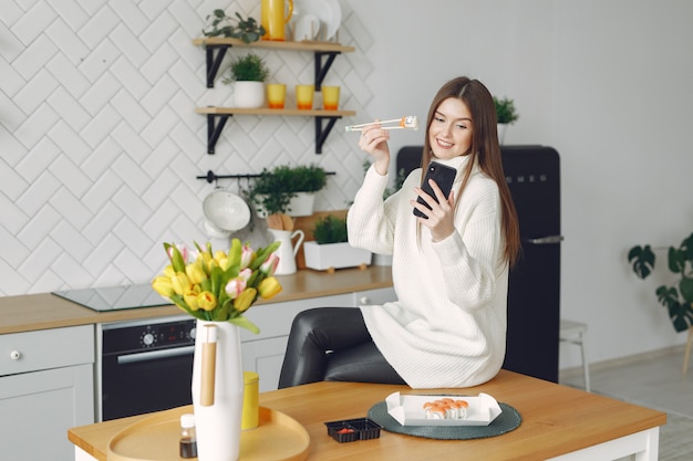 Ragazza che si siede a casa al tavolo con un sushi