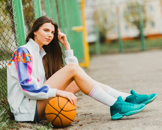 Ragazza che si siede con la pallacanestro