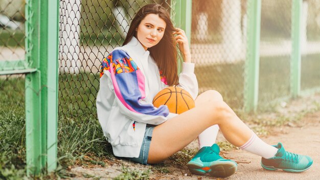 Ragazza che si siede con la pallacanestro