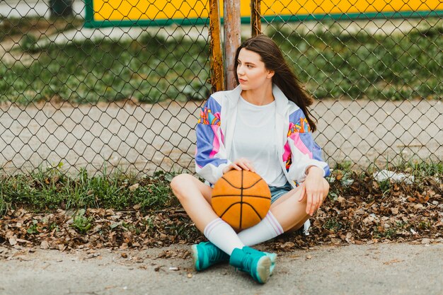 Ragazza che si siede con la pallacanestro