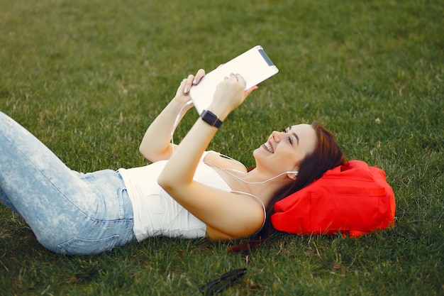 Ragazza che si siede in un campus universitario facendo uso di una compressa