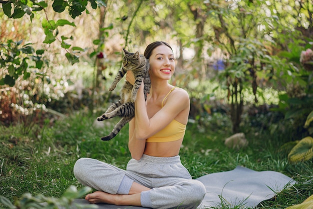 Ragazza che si siede in un parco estivo con simpatico gatto