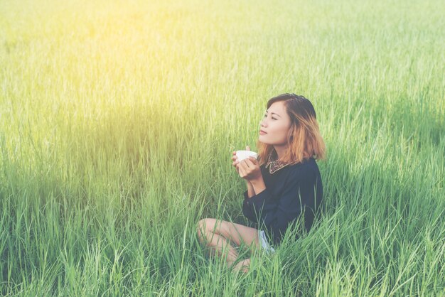 Ragazza che si siede nell&#39;erba