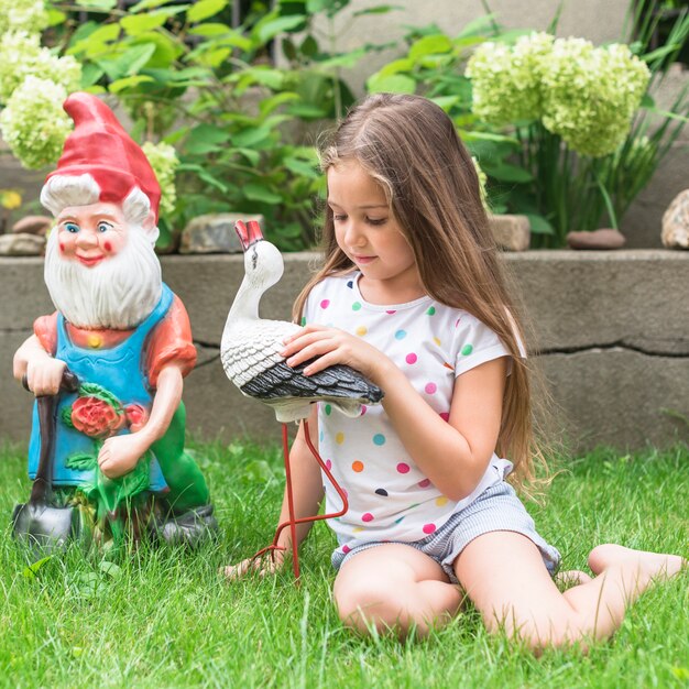 Ragazza che si siede sull&#39;erba verde che gioca con la statua