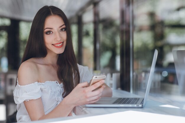 Ragazza che sorride con le labbra dipinte di rosso con un cellulare in mano