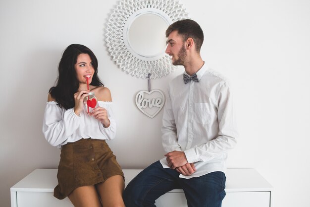 Ragazza che sorride mentre beve da un bicchiere con paglia rosso