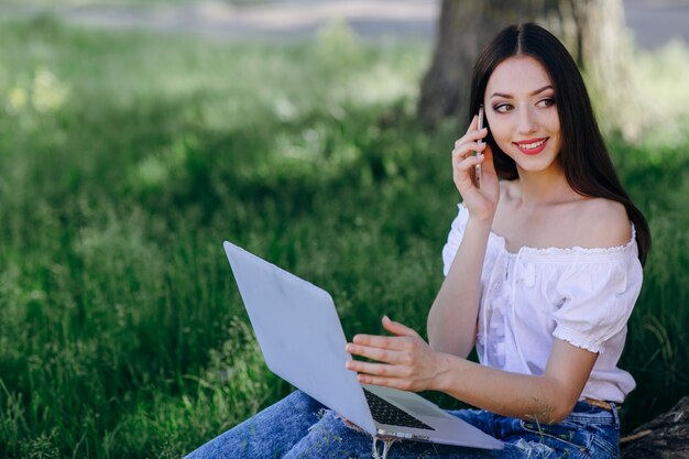 Ragazza che sorride mentre parla al telefono e avere un computer portatile