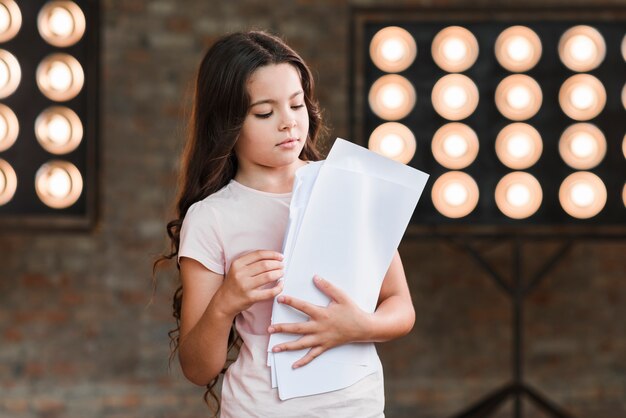 Ragazza che sta contro gli scritti della tenuta della luce della fase