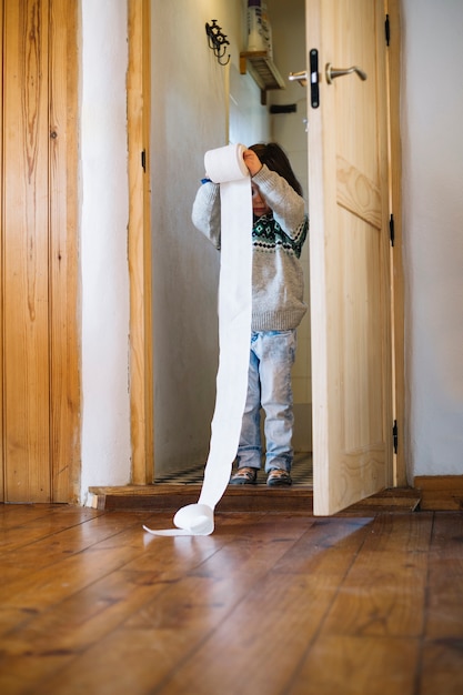 Ragazza che sta dentro il bagno che tiene la carta igienica