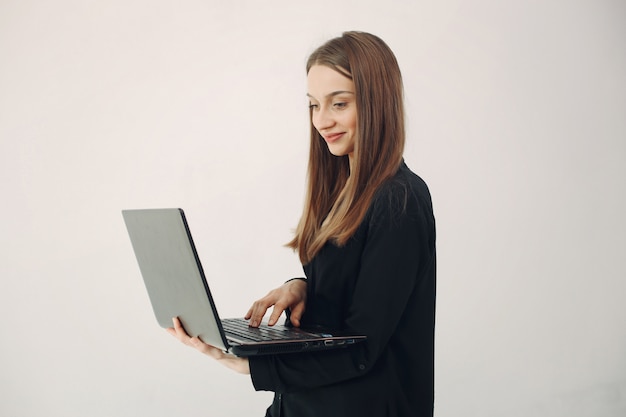 Ragazza che sta su una parete bianca con un computer portatile