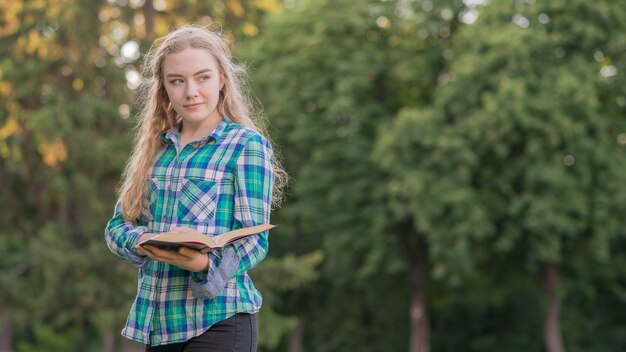 Ragazza che studia con il libro nel parco