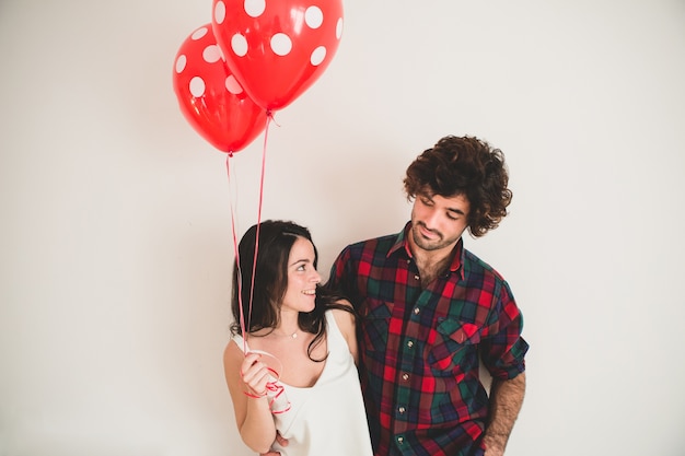 Ragazza che tiene due palloncini con il suo fidanzato accanto