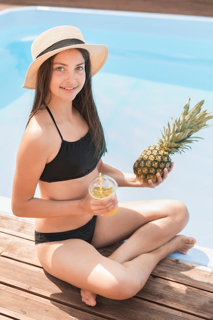 Ragazza che tiene frullato e ananas