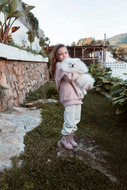 Ragazza che tiene il suo cane in braccio lungo tiro