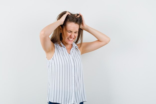 Ragazza che tiene le dita nei capelli in t-shirt, jeans e sguardo irritato. vista frontale.