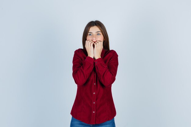 ragazza che tiene le mani sulla bocca in camicia casual e sembra spaventata.