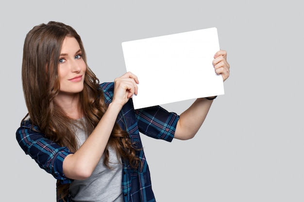 Ragazza che tiene tabellone per le affissioni bianco