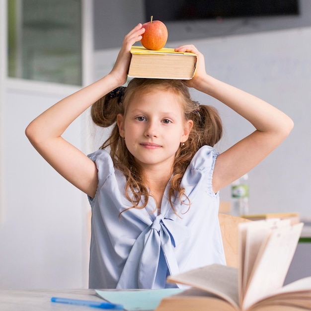 Ragazza che tiene un libro e una mela sulla sua testa