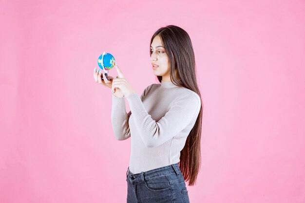 Ragazza che tiene un mini globo e lo studia attentamente