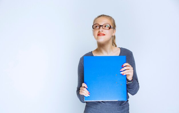 Ragazza che tiene una cartella blu e sogna.