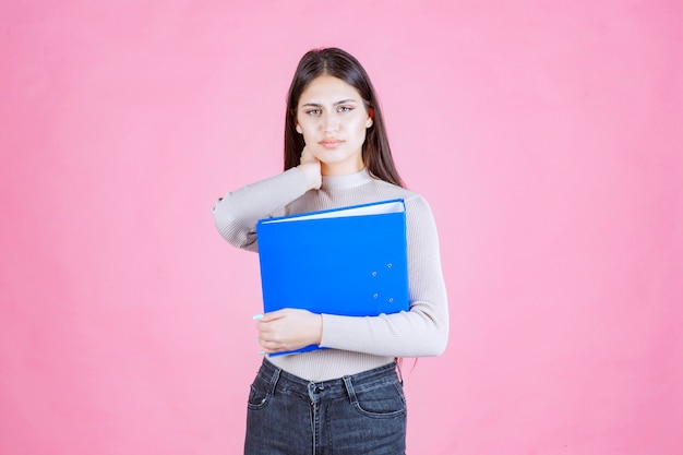 Ragazza che tiene una cartella di rapporto blu e sembra stanca