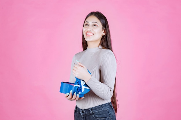 Ragazza che tiene una confezione regalo blu e sorridente