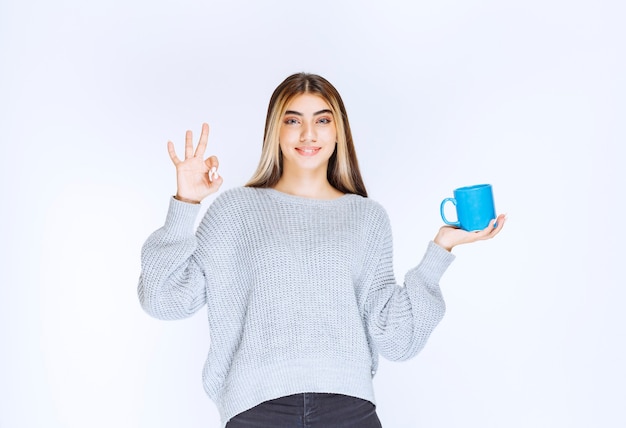 Ragazza che tiene una tazza di tè blu e si gode il gusto.