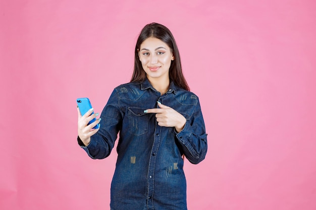 Ragazza che tiene uno smartphone nuovo di zecca e lo punta