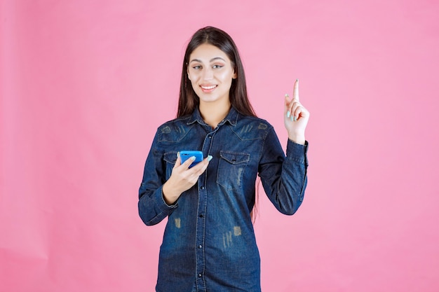 Ragazza che tiene uno smartphone nuovo di zecca e lo punta