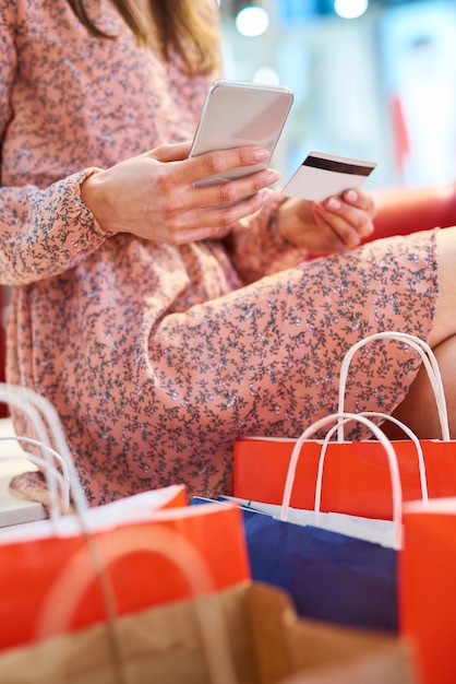 Ragazza che usa il cellulare e la carta di credito durante lo shopping online