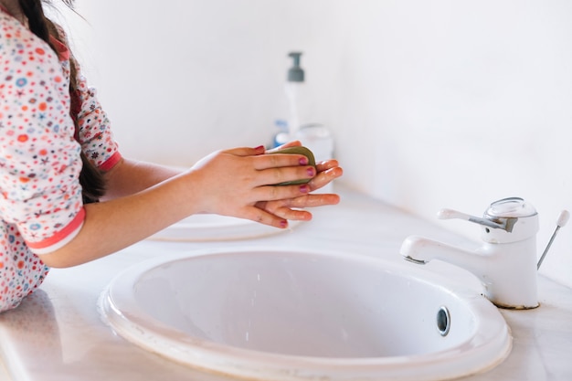 Ragazza che usando il sapone sulle sue mani in bagno