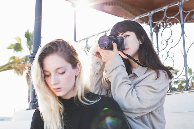 Ragazza che usando macchina fotografica agghiacciante con amico