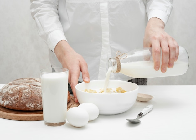 Ragazza che versa un po 'di latte in una ciotola con cereali