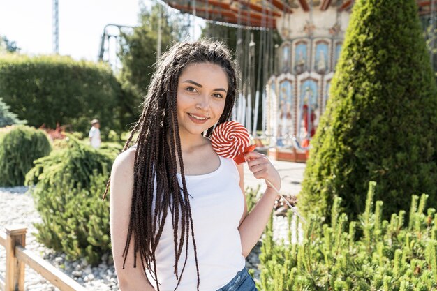 Ragazza con acconciatura treccia scatola con una lecca-lecca