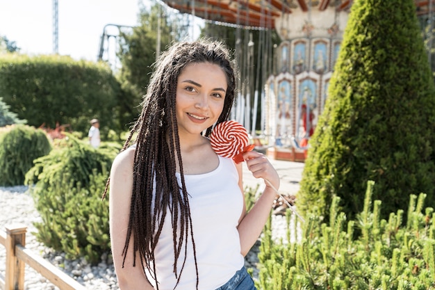 Ragazza con acconciatura treccia scatola con una lecca-lecca