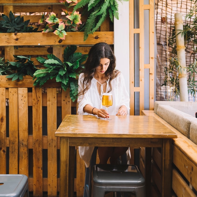 Ragazza con birra seduta al tavolo