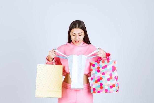 Ragazza con borse della spesa colorate aprendole e controllando.