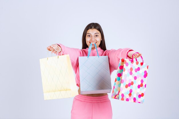 Ragazza con borse della spesa colorate tenendole nelle mani e in bocca.