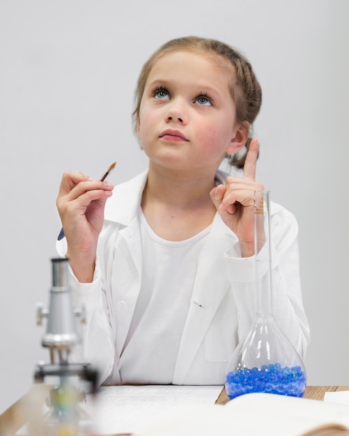 Ragazza con camice da laboratorio e microscopio