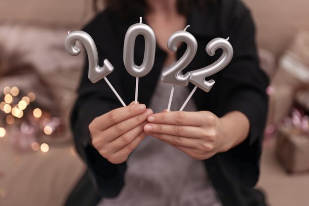 Ragazza con candele sotto forma di numeri 2022, concetto di celebrazione del nuovo anno.