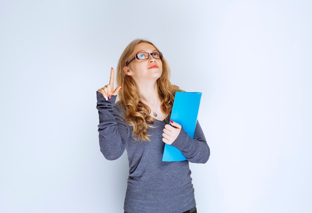 Ragazza con cartella blu che punta da qualche parte.